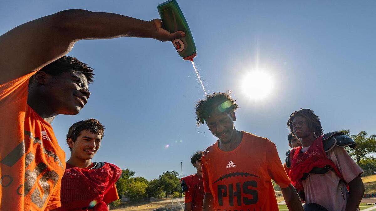 Abdel Mansour, 16, gets water poured on his head from his football teammates after practice at Fort Worth Polytechnic High School in Fort Worth on Thursday, Aug. 10, 2023.