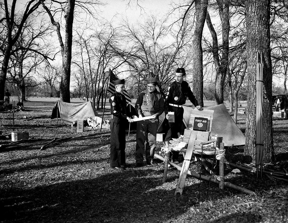 Feb. 13, 1954: Three members of Boy Scout Troop and Explorer Post 49 and the outdoor first aid display that helped them win first place in a scouting demonstration put on by the Horned Frog District of Longhorn Council. They are, left to right, Johnnie Grimmett, 2230 Mistletoe Dr.; Raymond Kinnear, 1651 Westmoreland, and Bill Miles, 2400 Park Pl.