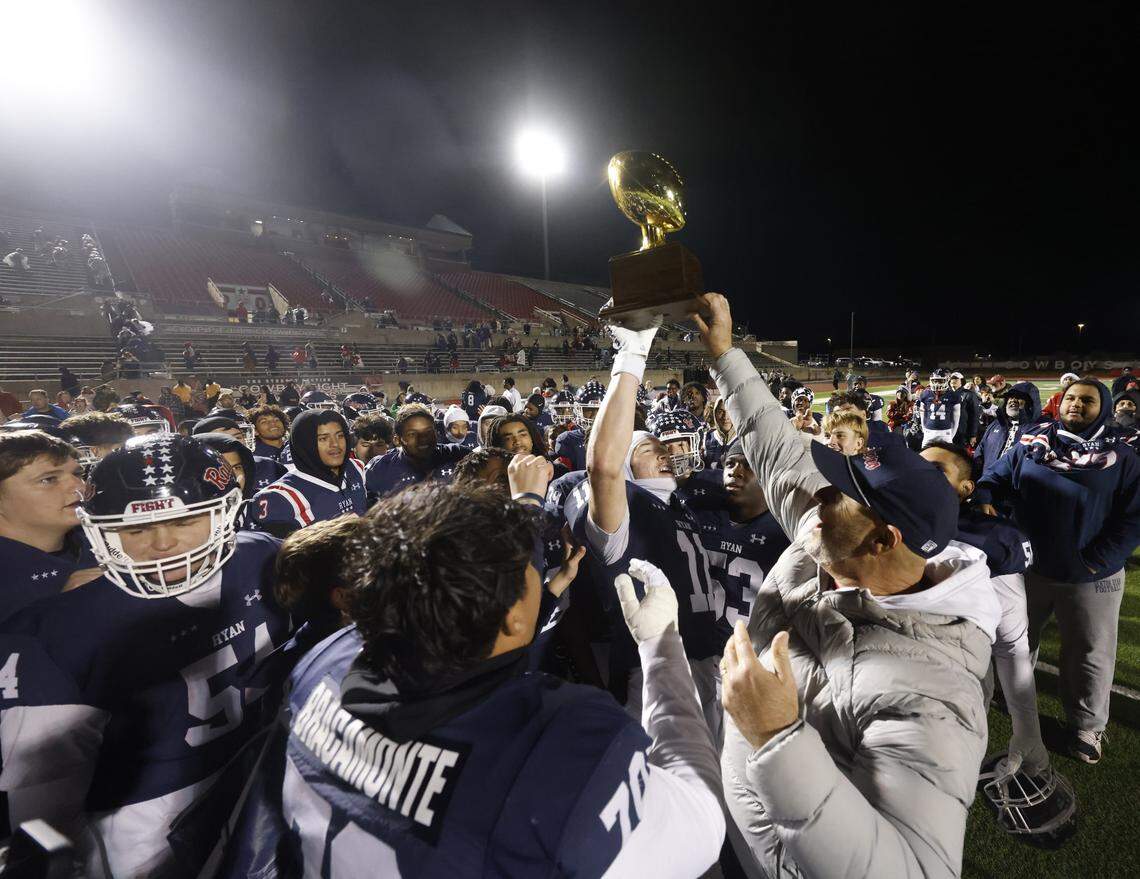 Denton Ryan head coach Dave Henigan hands the trophy to the Raiders after defeating Richland in a UIL Class 5A Division I Regional on Friday Nov. 28, 2025 at Buddy Echols Field in Coppell, Texas.