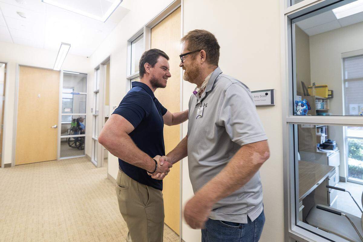 Educational Therapist Chandler Henderson greets Kevin Kirkland on a visit to the Centre for Neuro Skills in Fort Worth on Thursday, July 3, 2025. Kevin was Henderson's patient when he was going through occupational and physical therapy for his recovery.