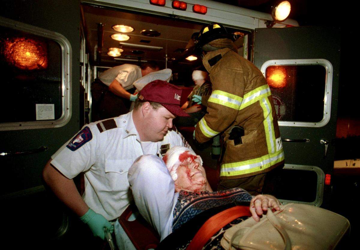 Emergency crews help an injured woman into an ambulance at the Farrington Field triage unit set up to help those injured in the hailstorm at Mayfest in Trinity Park May 5, 1995.
