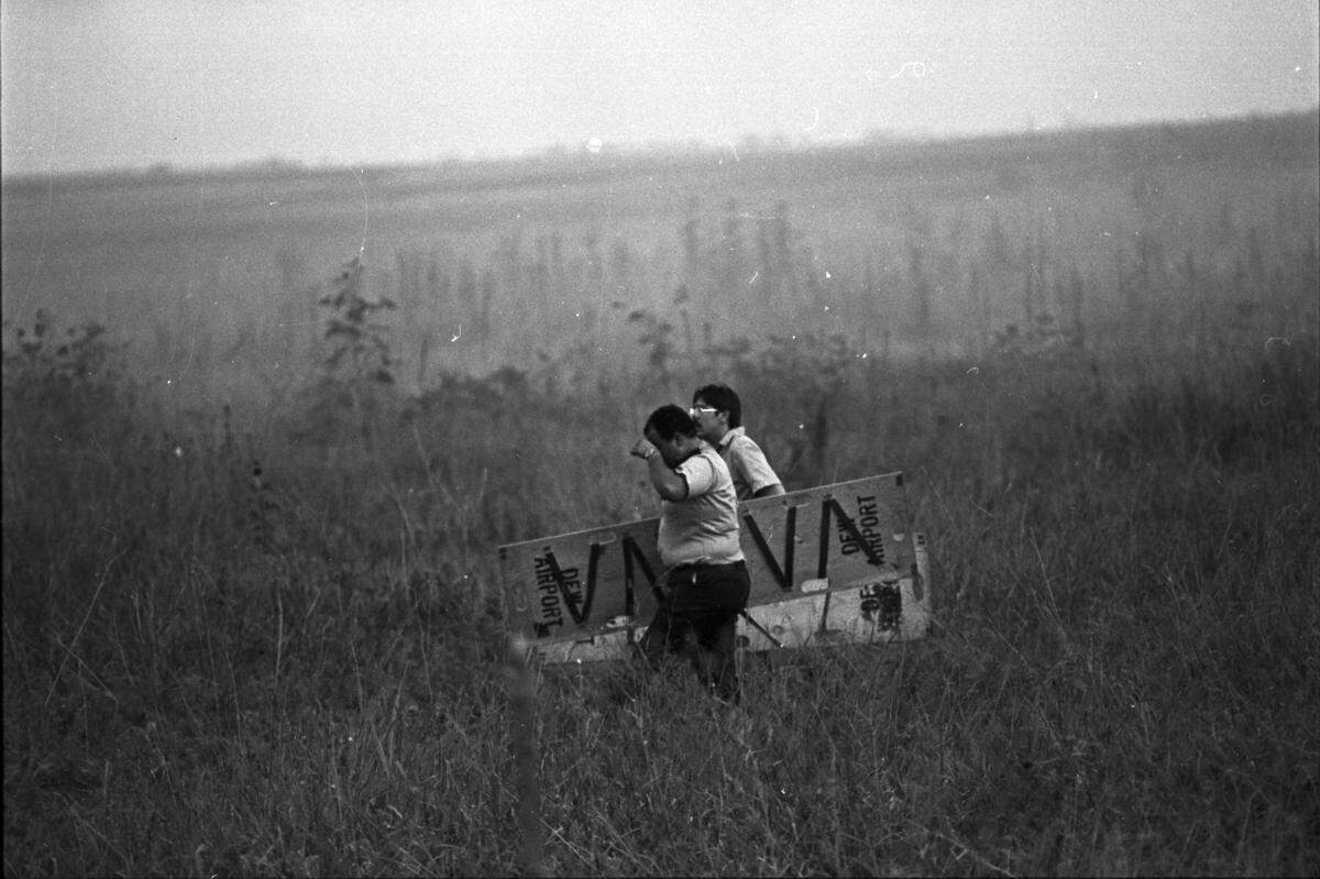 Black and white photo of two men caring a stretcher in a field.