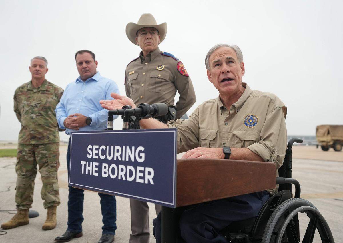 Gov. Greg Abbott speaks at a news conference as Texas Army National Guard troops deploy from Austin-Bergstrom International Airport on Monday May 8, 2023, to the Texas-Mexico border. National Guard soldier pictured on far left.