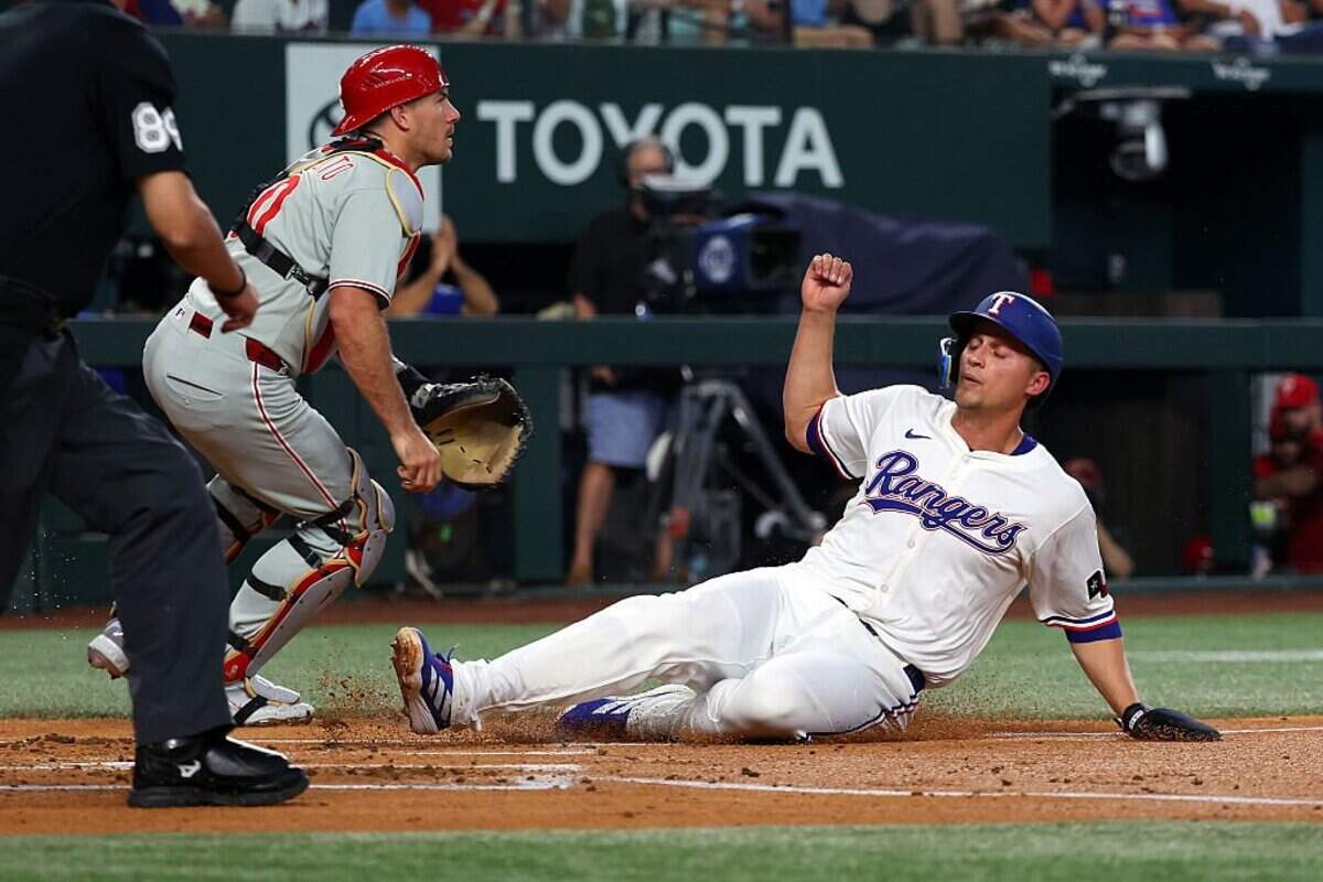 ARLINGTON, TEXAS - AUGUST 09: Corey Seager #5 of the Texas Rangers slides home to score against catcher J.T. Realmuto #10 of the Philadelphia Phillies in the first inning at Globe Life Field on August 09, 2025 in Arlington, Texas. (Photo by Richard Rodriguez/Getty Images)