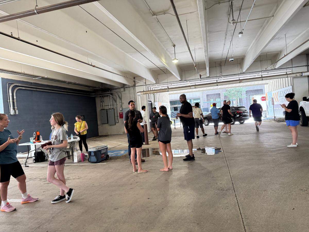 Tenants and employees of The Cooper apartments are standing in the parking lot on July 1, waiting to sign in to get into their units to collect personal items, and asking for more information.