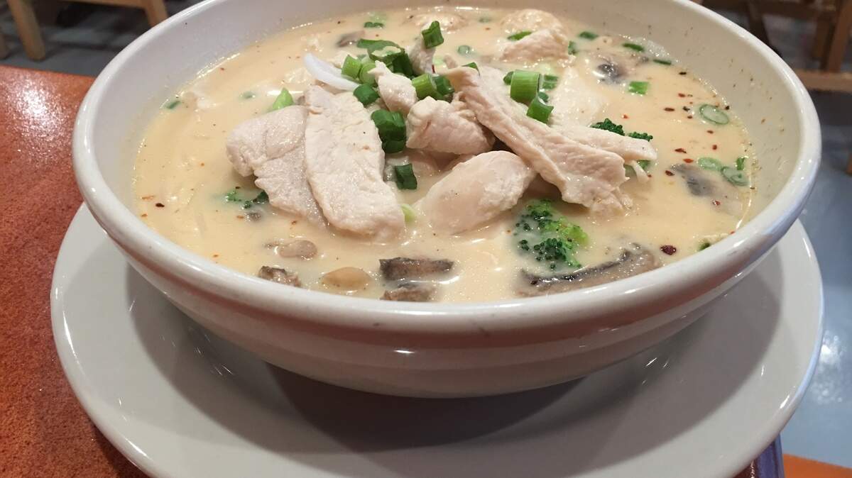 The tom kha noodle soup at Thai Orange Cuisine has a coconut milk base and white vermicelli noodles, with flecks of scallion and al dente broccoli. Here, chicken is the protein add-on.