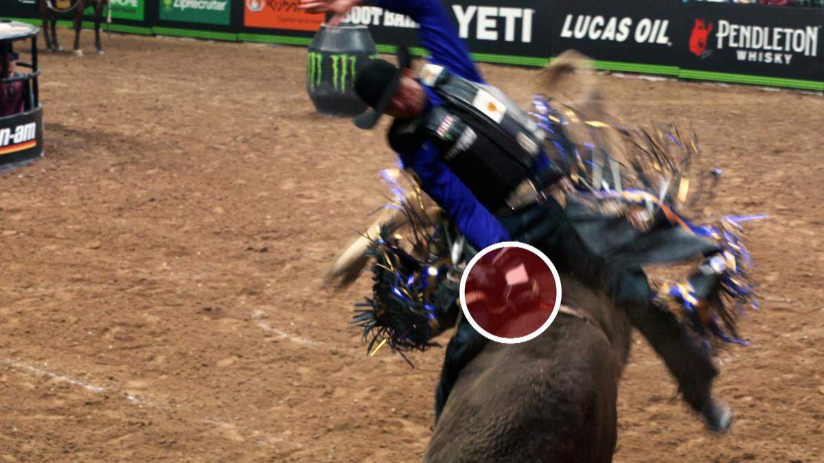 A bull rider keeping one hand on the rope and another in the air.