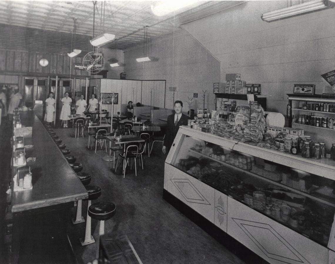 The interior of Carshon’s deli at 1010 Houston St. in 1951 shows owner Abe Applebaum near the deli counter, which is stocked on top with his wife’s homemade dill pickles and with halva, a Middle Eastern sweet. In the background, wearing white uniforms,  are two butchers and four waitresses.  