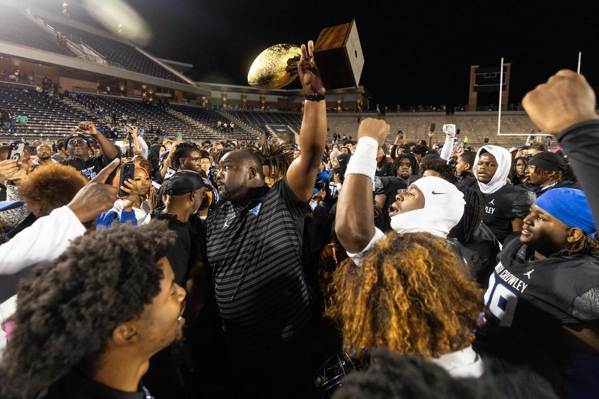 North Crowley head coach Ray Gates raises the trophy with his team after defeating Duncanville 36-34 in the Class 6A Division I state semifinal game at Eagle Stadium in Allen on Saturday, Dec. 14, 2024.