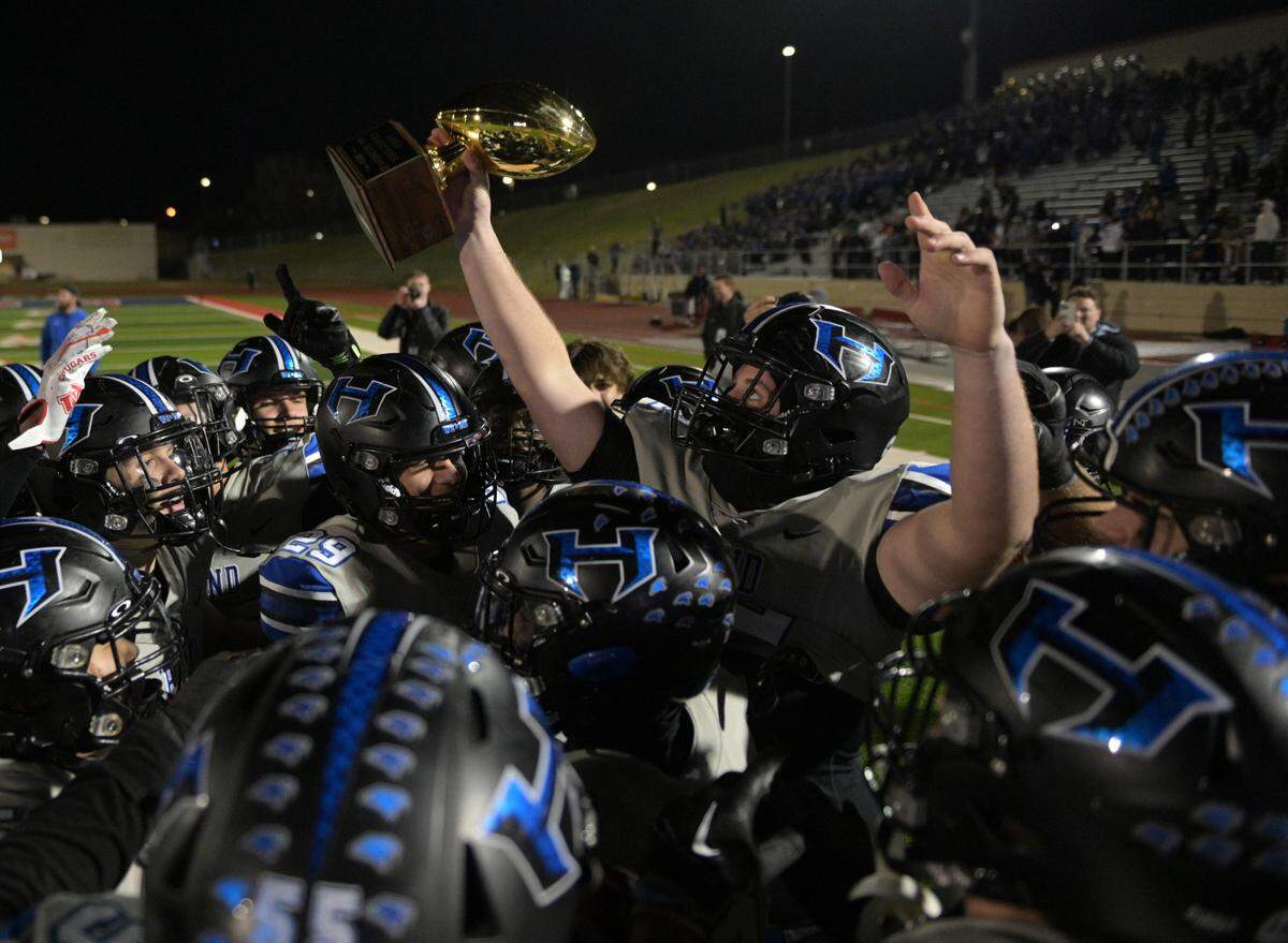 Hebron hawk offensive lineman Drew Deason (72) lifts the Arena Championship trophy during a UIL football playoff game against Bowie High School at Mustang-Panther Stadium in Grapevine, Texas on Friday, Nov. 22, 2024.
