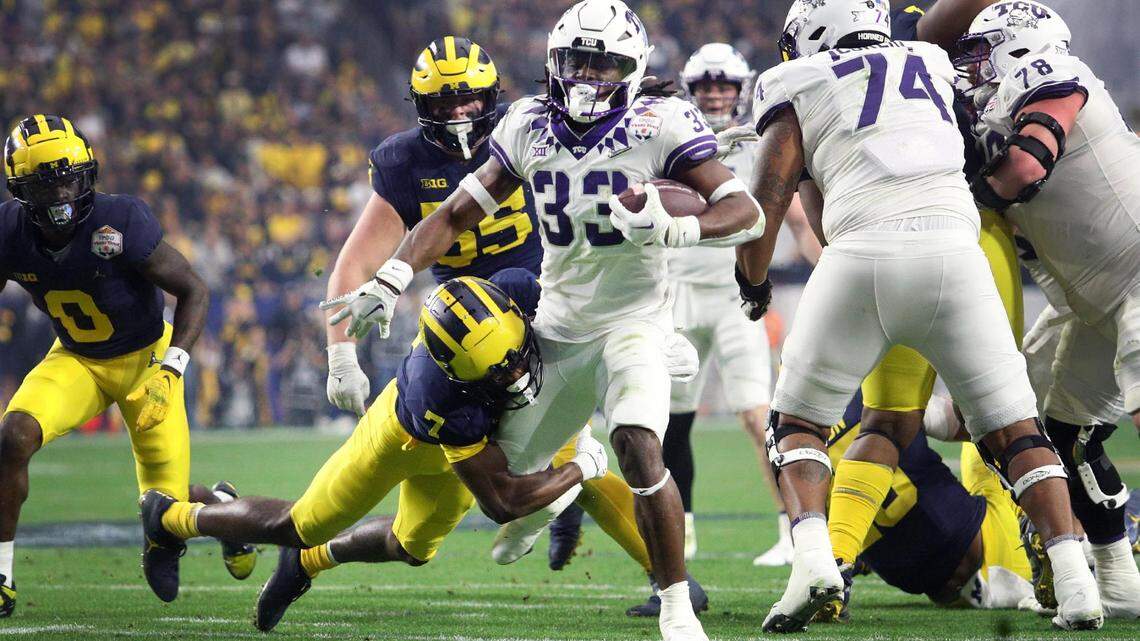 TCU running back Kendre Miller moves toward the end zone while Michigan safety Makari Paige defends at the Vrbo Fiesta Bowl at State Farm Stadium in Glendale, Ariz., on Dec. 31.