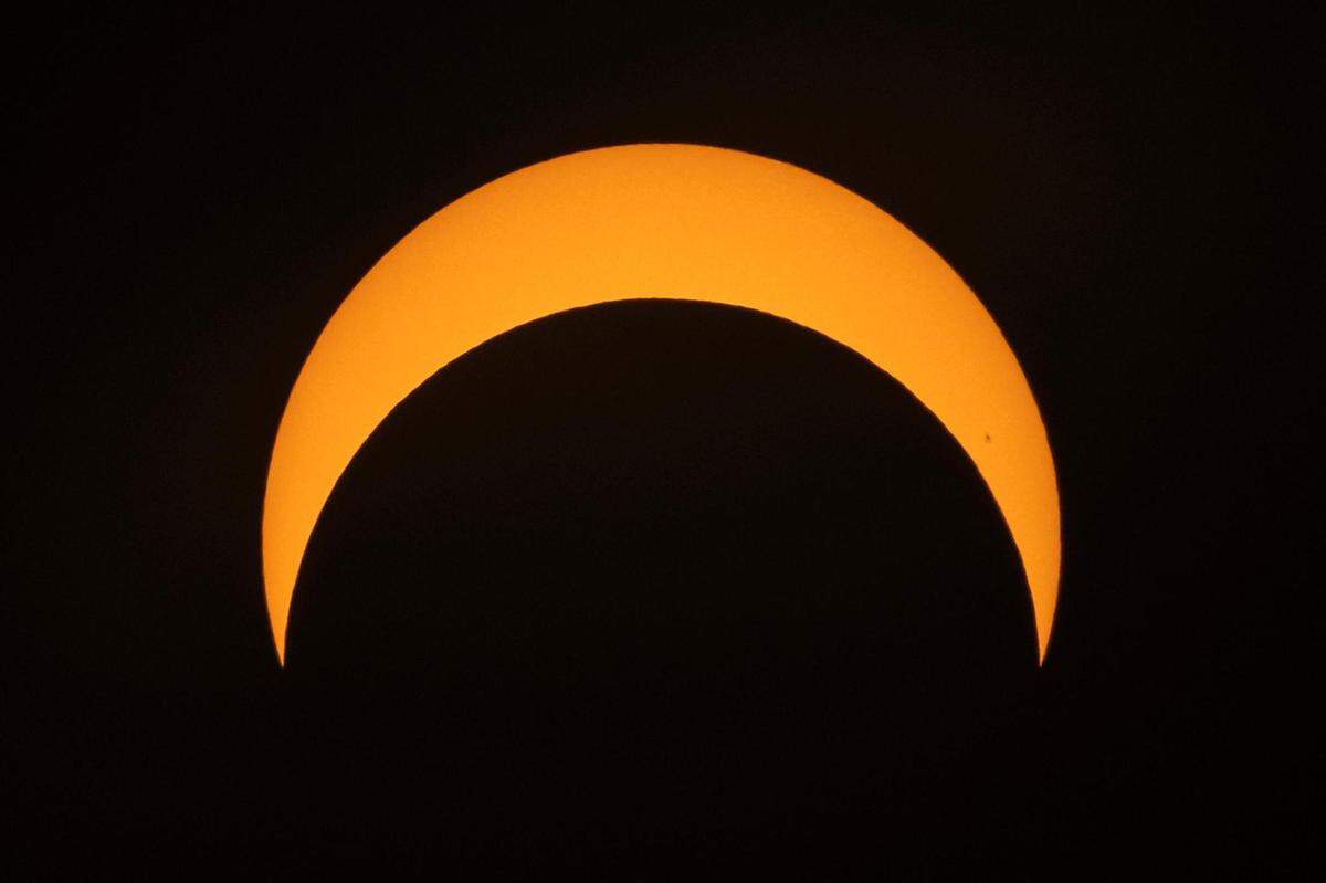 The moon begins its descent below the sun’s horizon during an annular solar eclipse in Fort Worth on Saturday, Oct. 14, 2023.