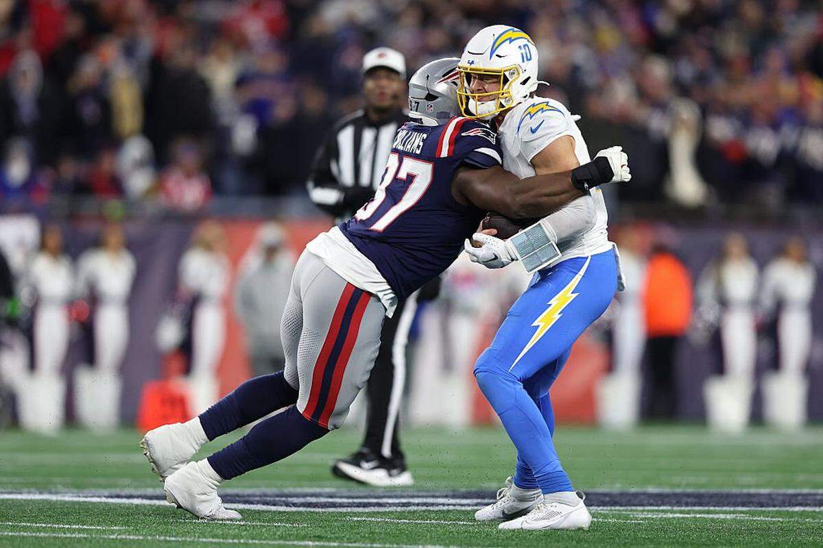 FOXBOROUGH, MASSACHUSETTS - JANUARY 11: Milton Williams #97 of the New England Patriots tackles Justin Herbert #10 of the Los Angeles Chargers during the fourth quarter of the AFC Wild Card Playoff game at Gillette Stadium on January 11, 2026 in Foxborough, Massachusetts.  (Photo by Adam Glanzman/Getty Images)