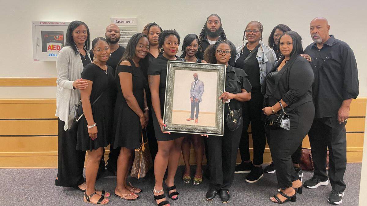 Timothy Shorter’s family holds up a portrait of him following sentencing in which the woman who killed him on New Year’s Day 2019 pleaded guilty in exchange for 10 years’ probation, a deal the family called insulting and disrespectful.