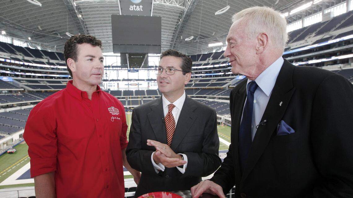 NFL team owners Jerry Jones of the Dallas Cowboys, right, and Daniel Snyder of the Washington Redskins, center, enjoy a slice of pizza with Papa John’s founder John Schnatter as part of a Papa John’s video shoot at Cowboys Stadium in 2010. On Wednesday, Forbes reported that Schnatter used a racial slur during a conference call in May.