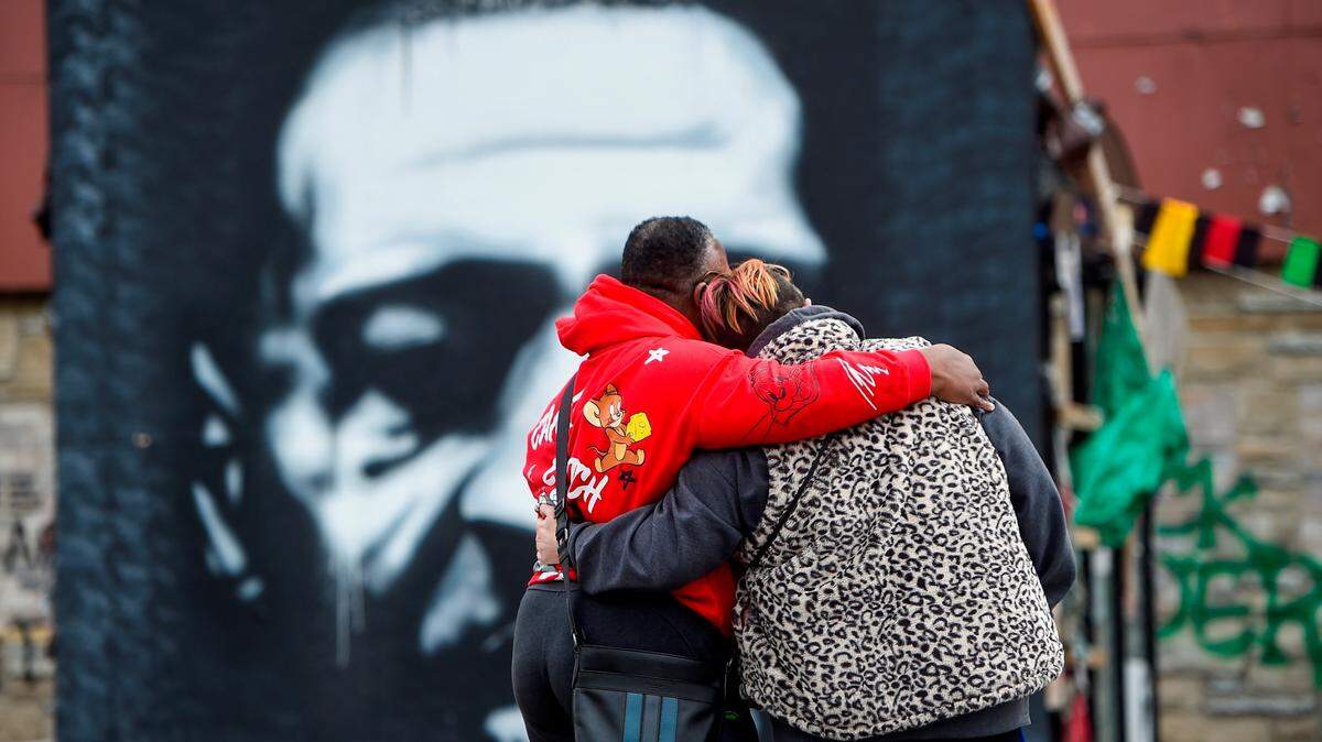 Una pareja se detiene por un momento frente a un retrato de George Floyd en el segundo día de deliberaciones en el juicio por asesinato del ex oficial de policía de Minneapolis Derek Chauvin, quien fue encontrado culpable de tres cargos el martes.