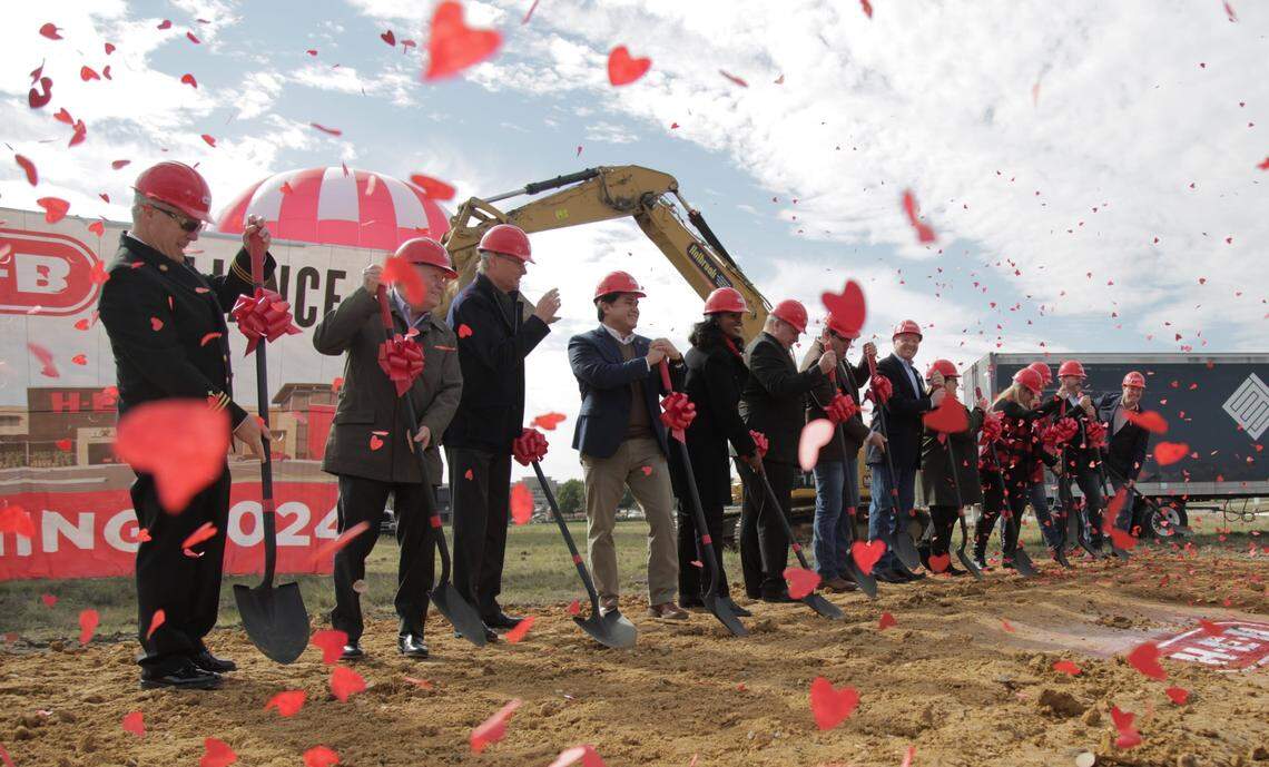 People wearing hard hats at a groundbreaking with confetti falling all around. 