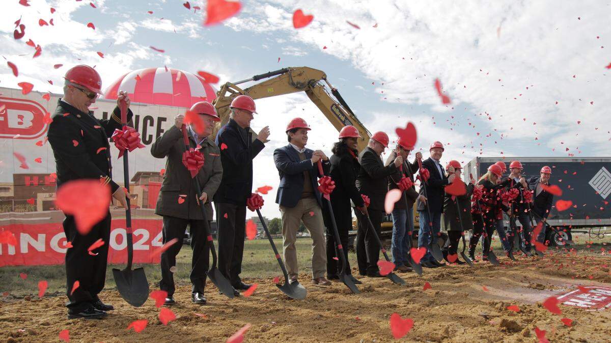 People wearing hard hats at a groundbreaking with confetti falling all around. 