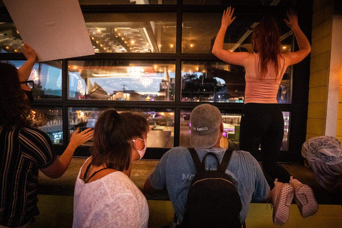 Protesters stop to look at customers inside Your Mom’s House bar Monday, June 8, 2020, in Fort Worth.