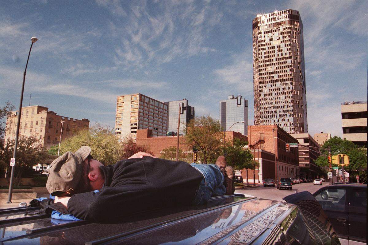 Videographer Tom Jachman {cq} with the FOX News Channel rests while, waiting for the next live shot, watches broken windows being knocked off the Bank One tower.