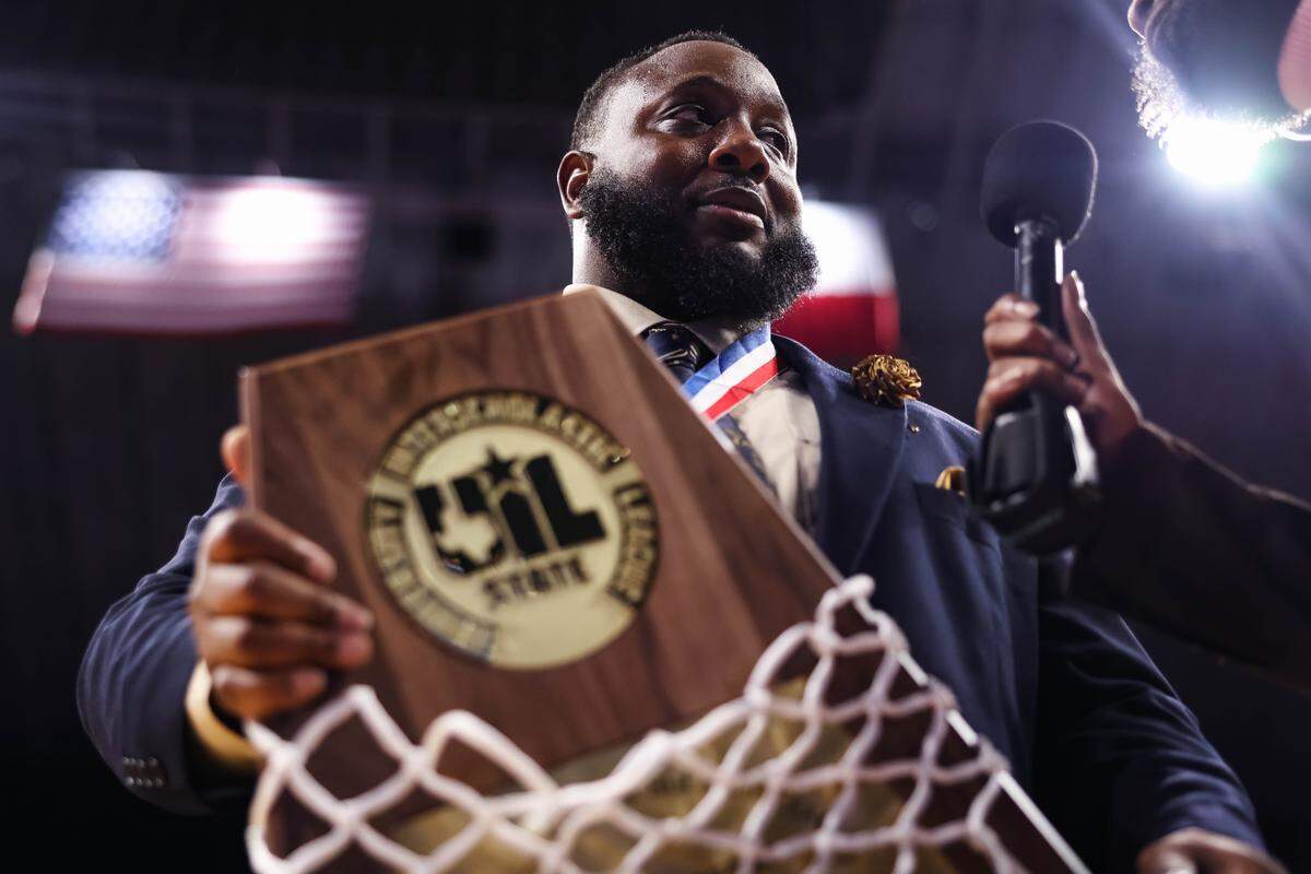 Mansfield Summit head coach Emund Prichett holds the championship trophy during a postgame interview after the Class 5A Division II state championship game against Beaumont United on Saturday at the Alamodome in San Antonio.