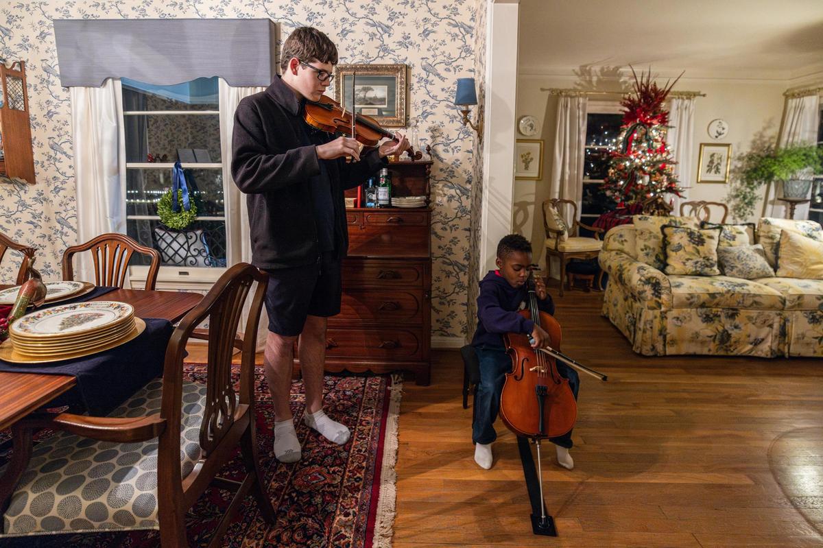 High school sophomore Andrew James, 16, plays the violin while his younger brother George, 6, plays the cello at their family residence in Fort Worth on Dec. 12, 2024.