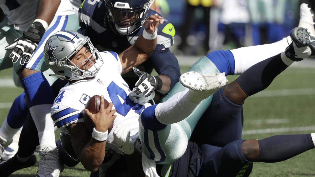 Dallas Cowboys quarterback Dak Prescott (4) is sacked by Seattle Seahawks defensive end Dion Jordan, top, and defensive tackle Jarran Reed, bottom, during the first half of an NFL football game, Sunday, Sept. 23, 2018, in Seattle.