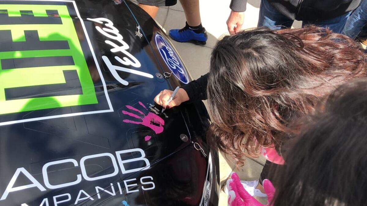 Emily Avila signing the No. 51 car