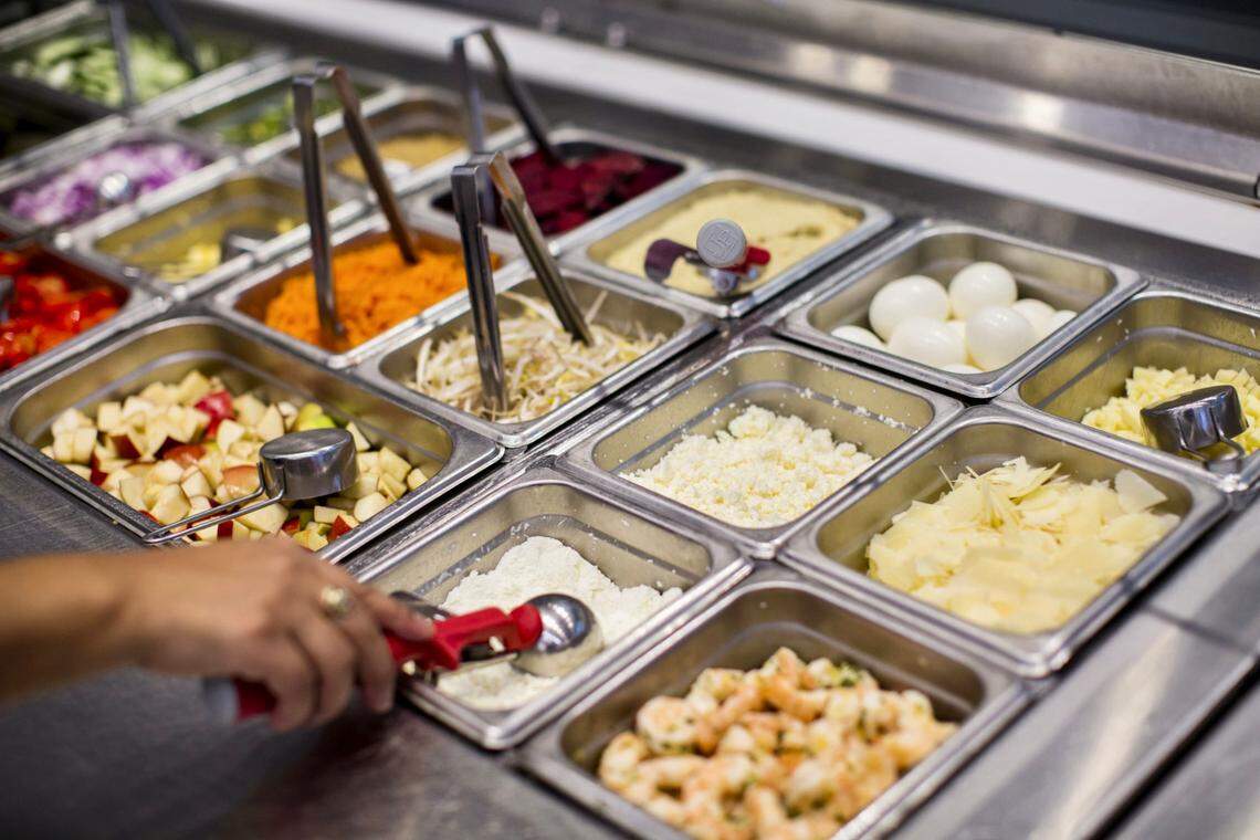 A worker scoops an ingredient for an order from the salad bar inside a Sweetgreen restaurant in Boston.