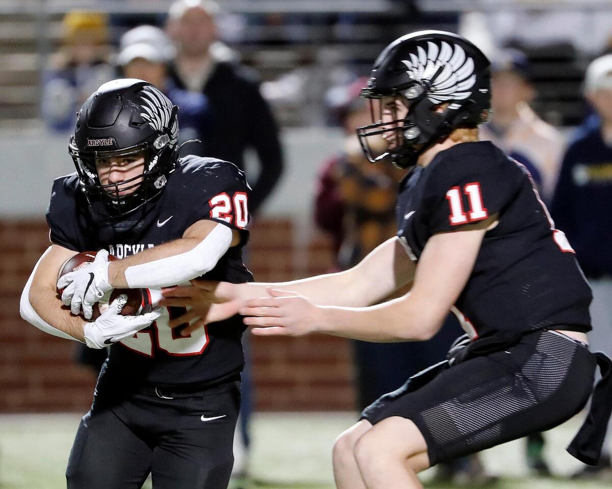 Argyle running back Landon Farris (20) takes the ball from quarterback John Gailey (11) during a high school Class 4A Division 1 Regional football game at Newsom Stadium in Mansfield, Texas, Friday Nov. 26, 2021. Argyle led by seven at the half. (Special to the Star-Telegram Bob Booth)
