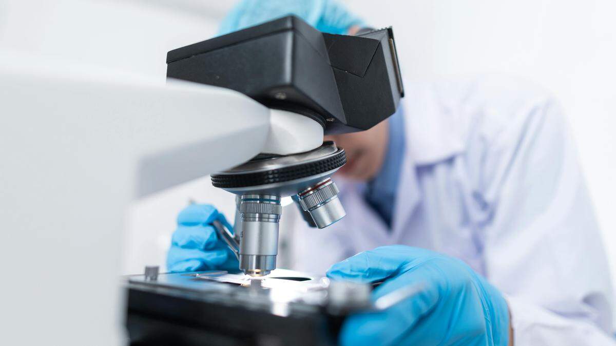 A scientist looking at a microscope.