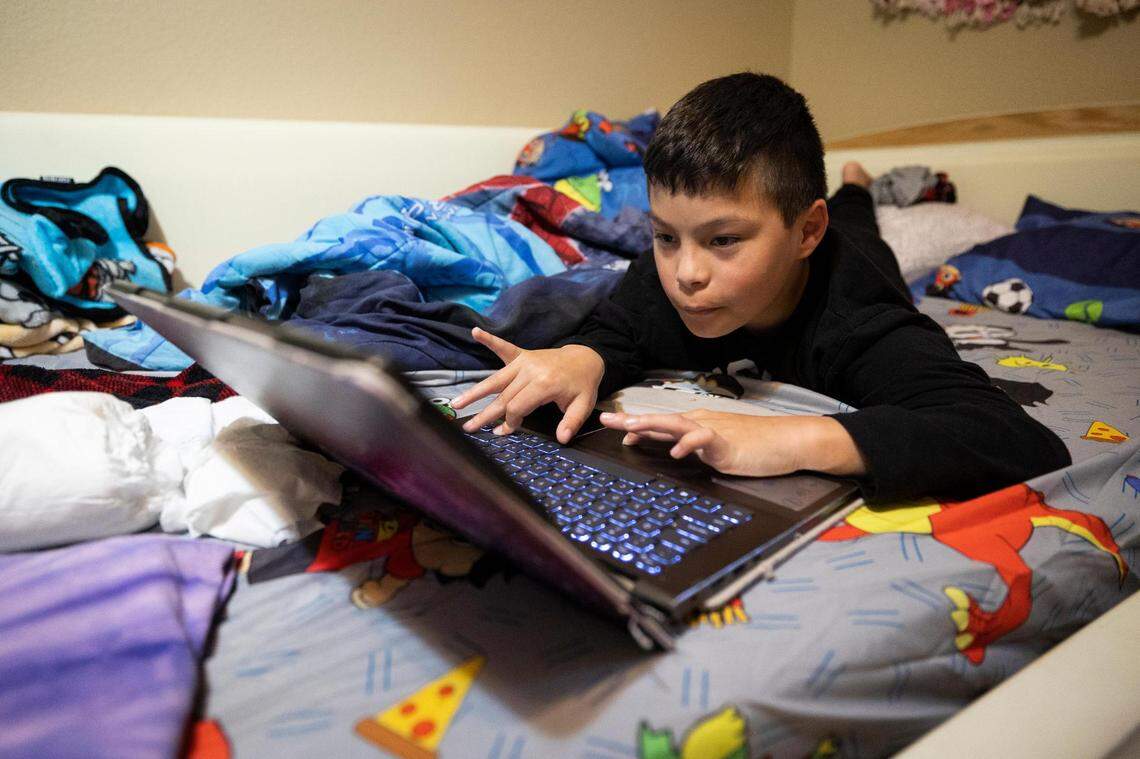 Santiago Piñón plays on a laptop on his bed. He and his sisters each have cerebral palsy, need special education services and have had English-learning services in the past.