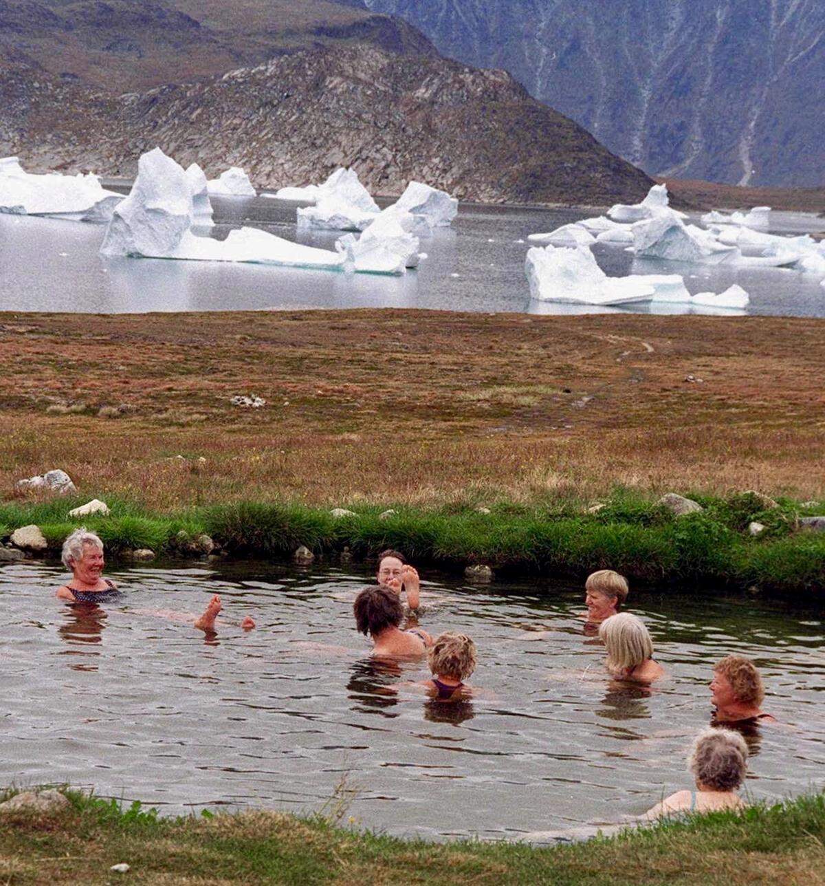 Bathers enjoy a hot spring pool on a small island in Greenland as icebergs float by in a nearby fjord in 1996.