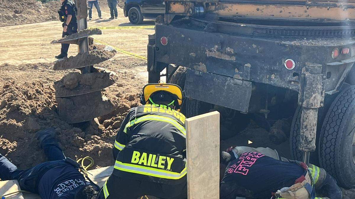 Firefighters work to recover a construction worker who died in a collapsed hole, officials said.
