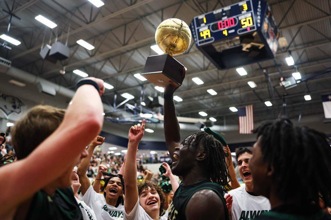 Birdville forward Gabriel Zachariah (0) holds the trophy in the air surrounded by his teammates after clinching a spot in the state semifinals after a 50-49 UIL Class 5A Division I regional final win against Denton at Flower Mound High School in Flower Mound, Texas, Friday, March 6, 2026.