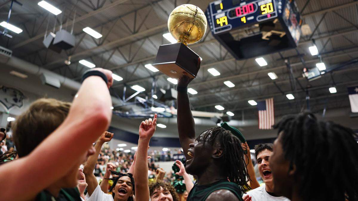 Birdville forward Gabriel Zachariah (0) holds the trophy in the air surrounded by his teammates after clinching a spot in the state semifinals after a 50-49 UIL Class 5A Division I regional final win against Denton at Flower Mound High School in Flower Mound, Texas, Friday, March 6, 2026.