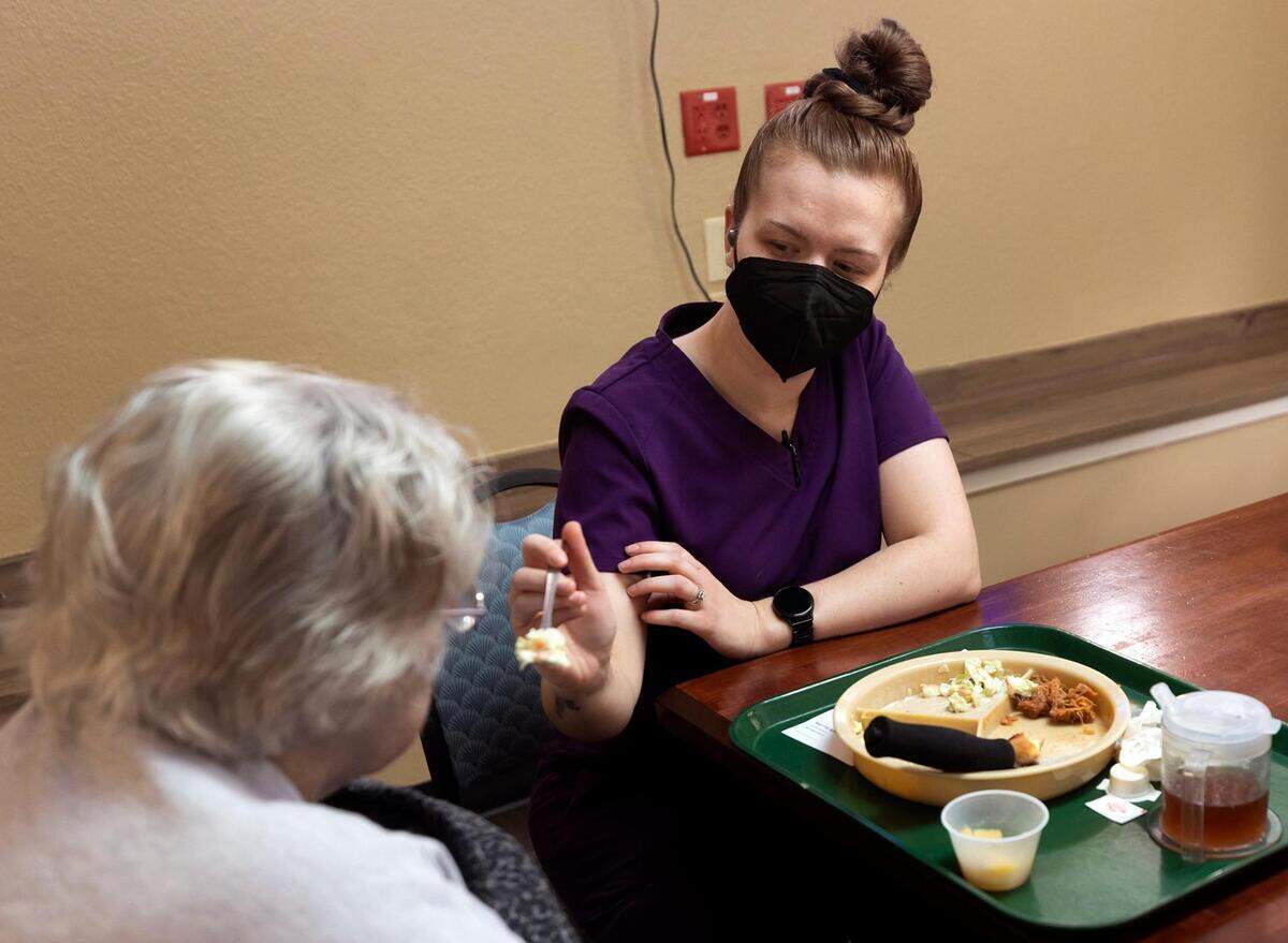 Certified nursing assistant Kirsten Delapaz helps a resident eat her lunch at Heritage at Turner Park. 