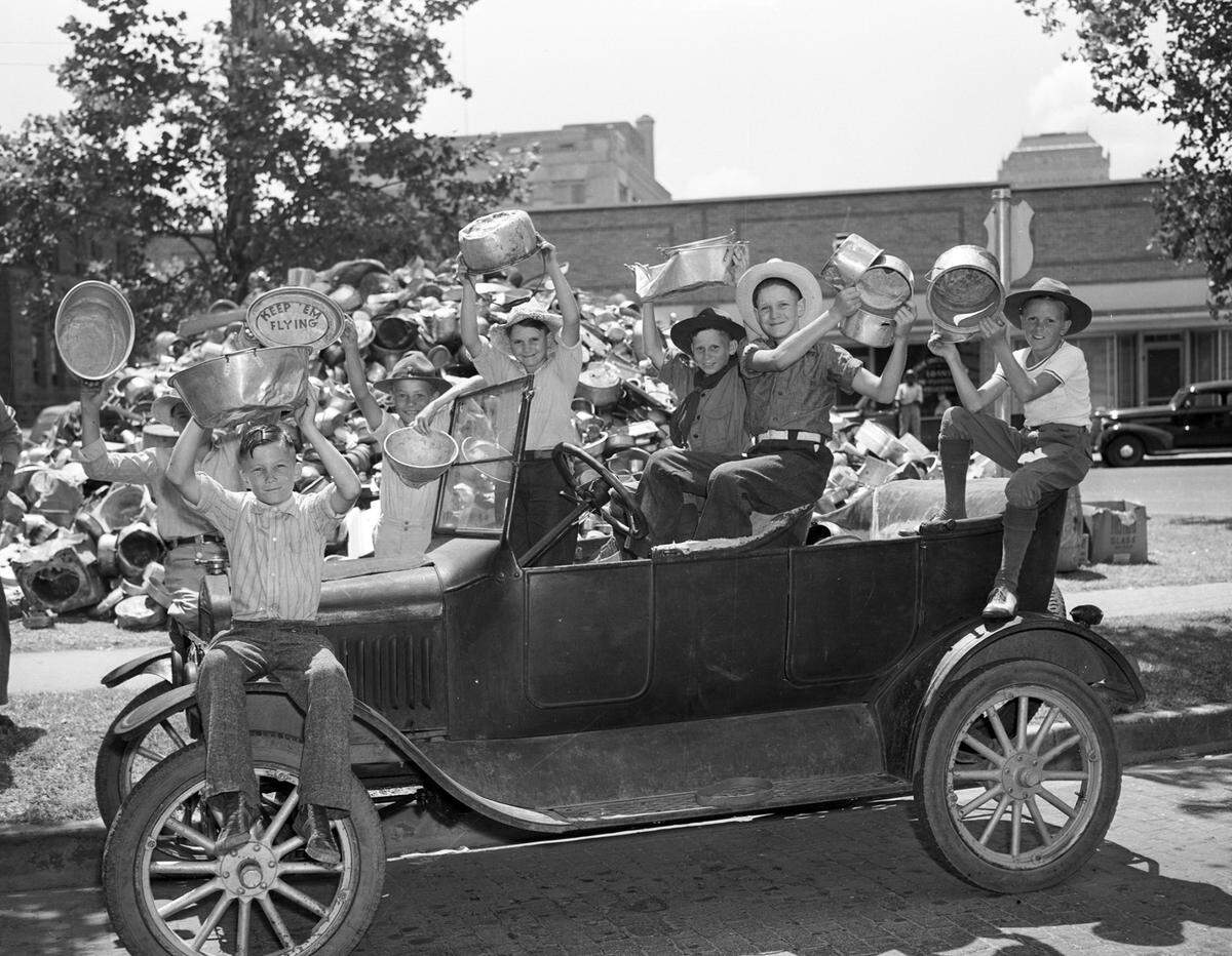 July 28, 1941: Holding some of the aluminum pieces they collected from Everman, Texas, residents are seven Boy Scouts from Troop 120, with the Model T car that brought them to the Fort Worth collection center at Peter Smith Park. The aluminum donations will be used for the national defense program. Behind them is a pile of the aluminum collected so far. At the far left, front, is Cecil Corn, 11. Others, left to right, are Roy Thomas, 12 (directly behind Corn); Weldon Pittman, 13; Earl Ray Smithey, 10; Robert Lee Wylie, 12; Edwin Smithey, 13; and Billy Owen, 13.