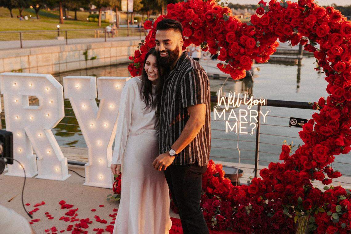 Ward Sakeik and her husband, Taahir Shaikh, celebrate their engagement. They pose in front of a heart backdrop constructed with roses.