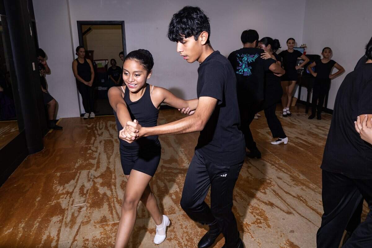 Alex Garcia and Sara Contreras, dressed all in black, dance hand in hand.