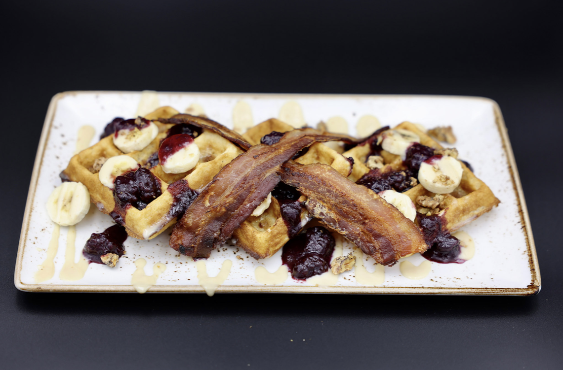 A waffle dish with bacon and fruit from Press Cafe’s brunch menu.