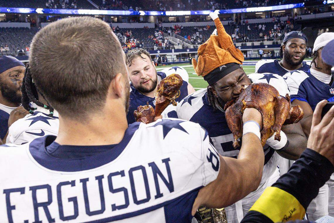Cowboys tight end Jake Ferguson (87) feeds his teammate Tyler Booker the turkey on his hand after winning an NFL game between the Dallas Cowboys and the Kansas City Chiefs at AT&T Stadium in Arlington on Thursday, Nov. 27, 2025. The Cowboys won 31-28.