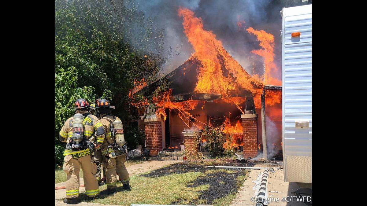 A house in flames with firefighters standing around