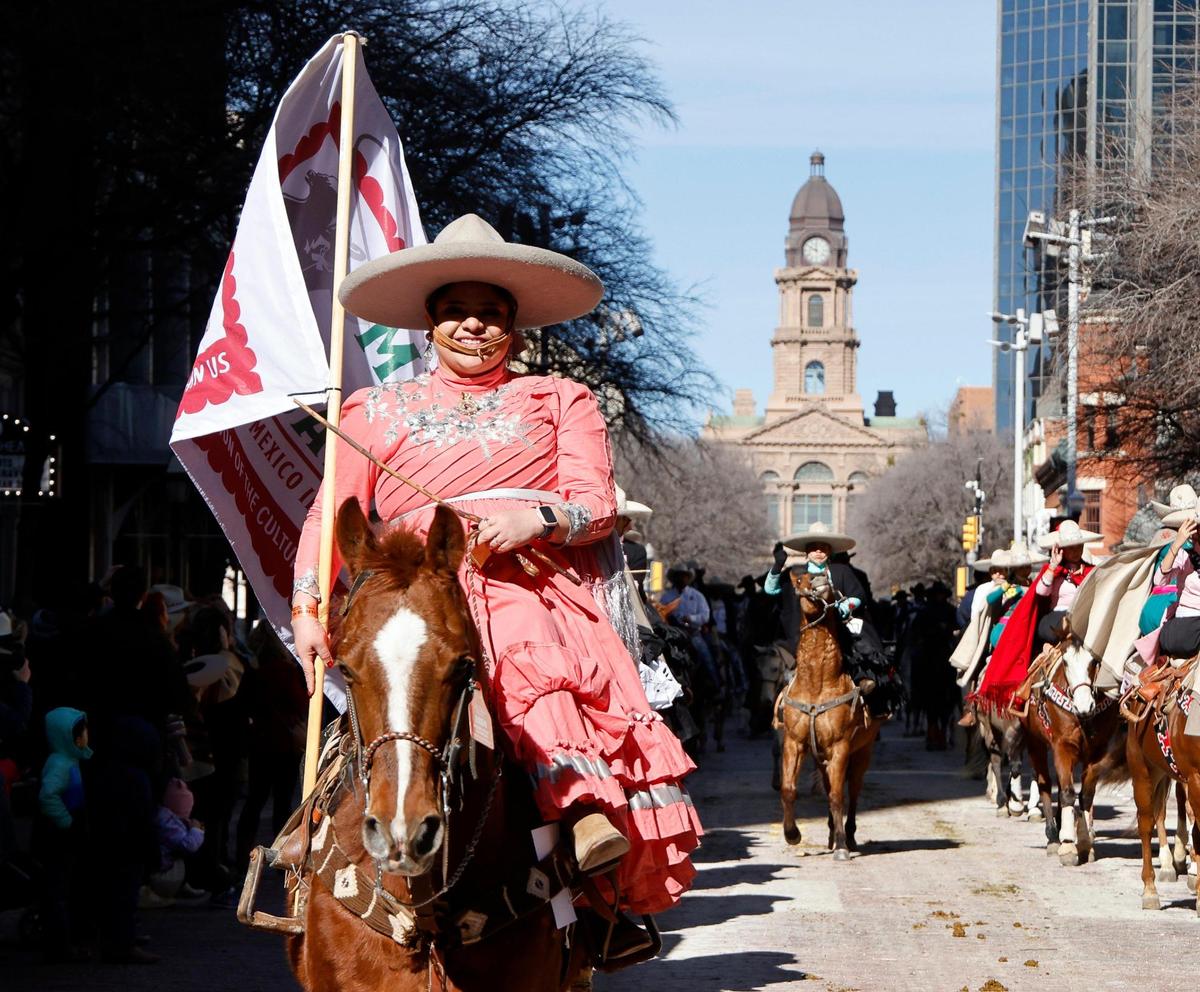 Female vaqueros ride side-saddle down Main Street.