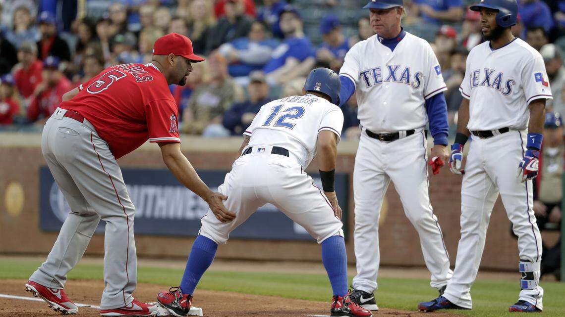 Angels first baseman Albert Pujols, left, helps Texas Rangers' Rougned Odor who suffered a left hamstring injury getting back to first in the first inning of Monday's game in Arlington. Rangers coach Steve Buechele and Elvis Andrus, right, watch.