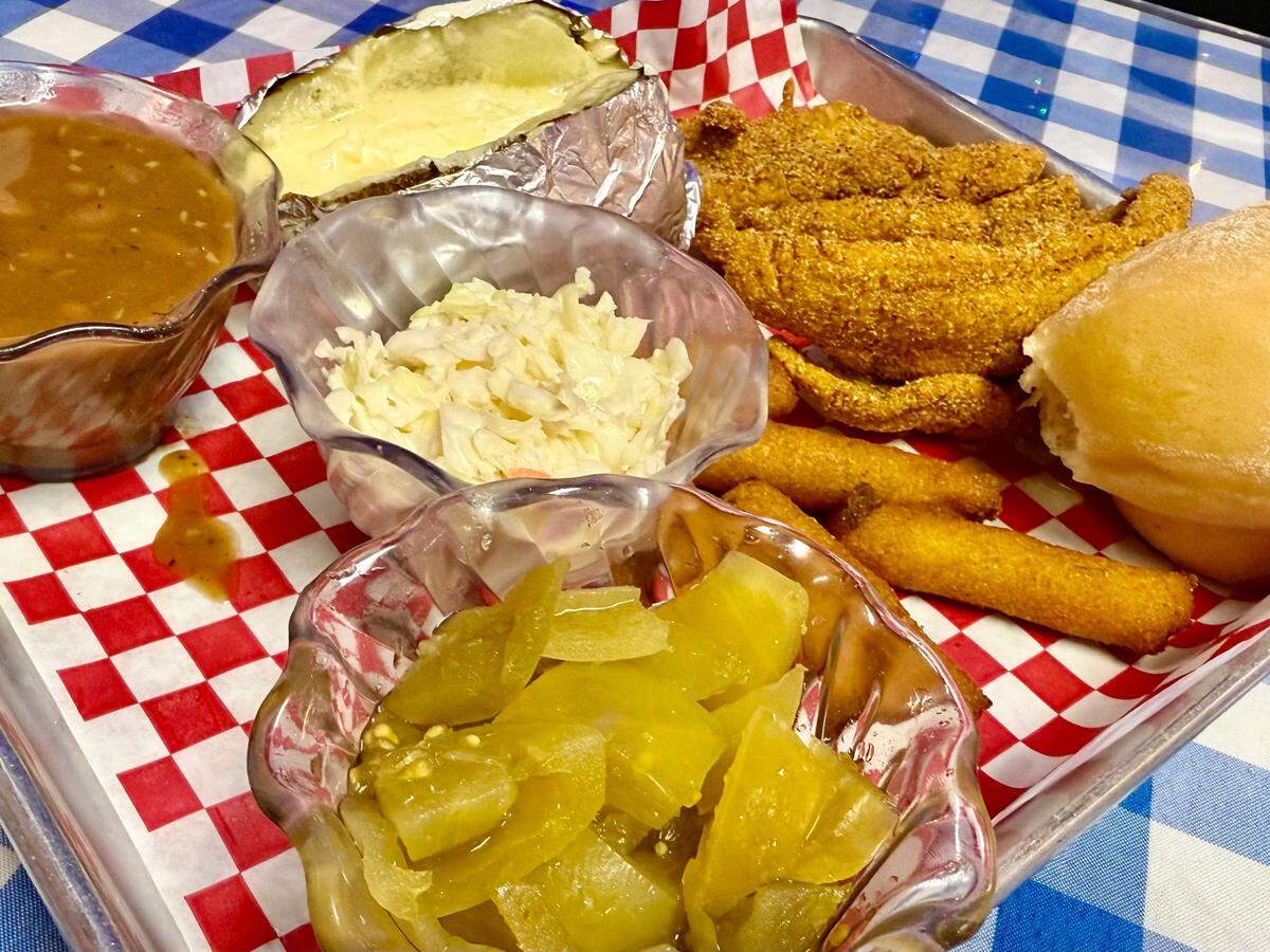 A spicy catfish mini-strips platter with green tomato relish, pintos, baked potato, roll and hush puppies at Catfish Sam’s in Arlington, Texas, April 19, 2025.