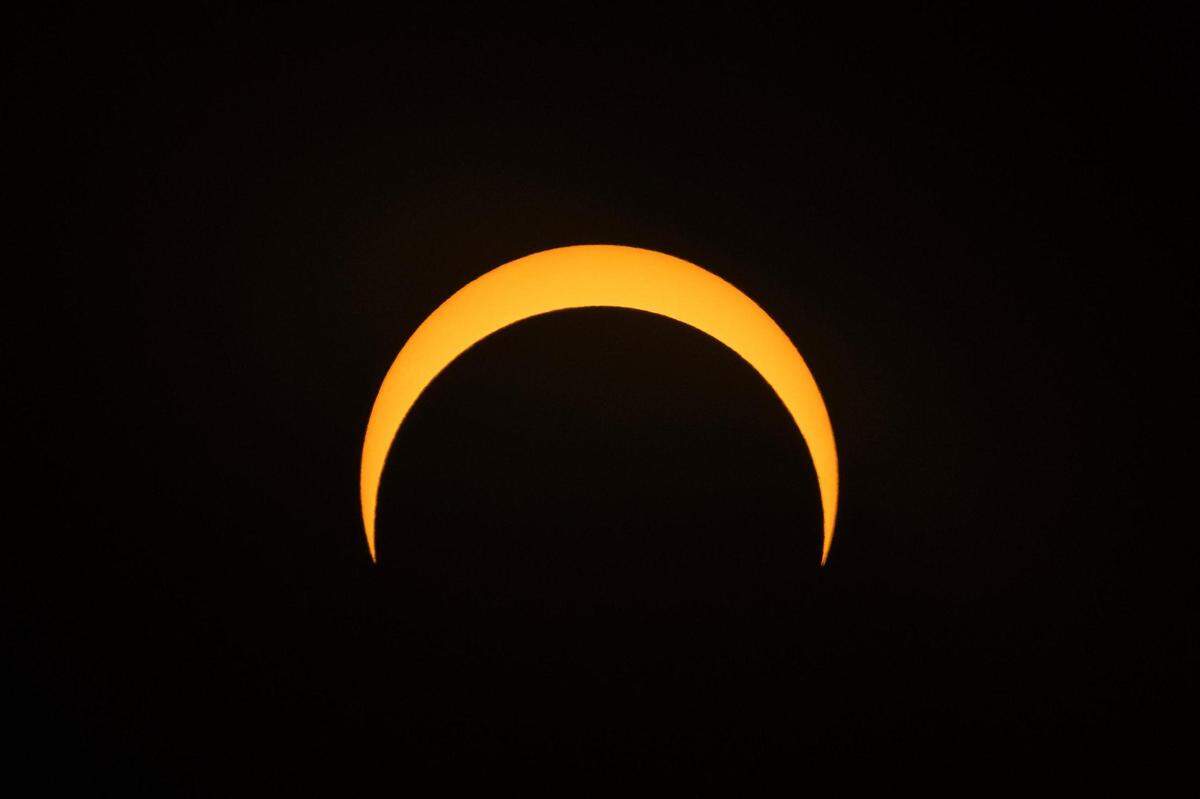 The moon begins its descent below the sun’s horizon during an annular solar eclipse in Fort Worth on Saturday, Oct. 14, 2023.
