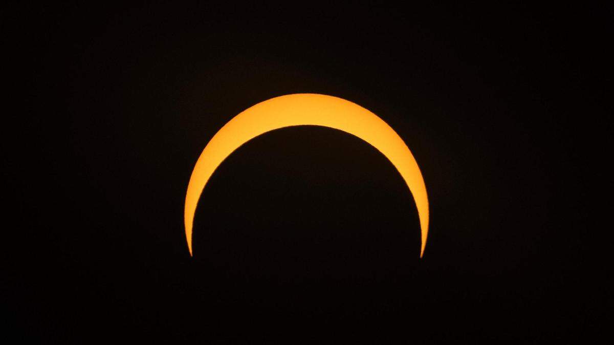 The moon begins its descent below the sun’s horizon during an annular solar eclipse in Fort Worth on Saturday, Oct. 14, 2023.