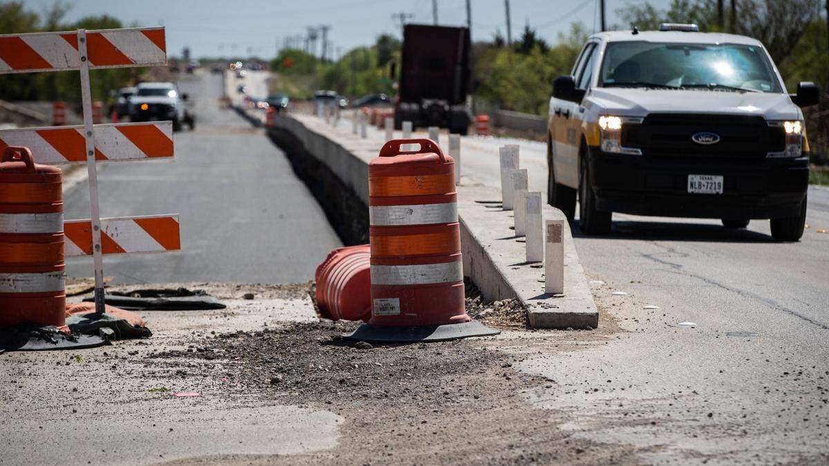 A road under construction with a car passing by. 
