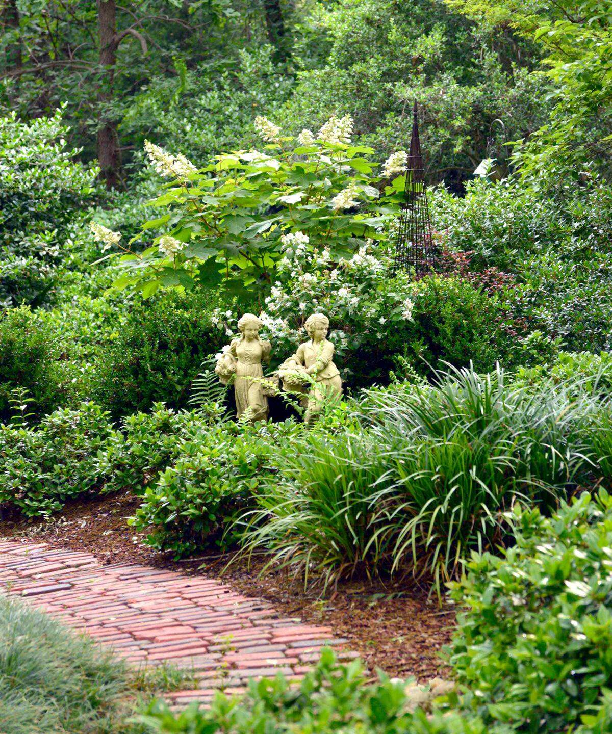 Statues are focal point of the Sperry backyard garden, set off by antique street pavers and oakleaf hydrangeas and mock oranges in bloom.